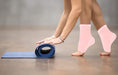 A woman standing on a yoga mat with Dr. Arthritis Copper Infused Foot Sleeves on her feet.