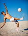 A man kicking a Copper Infused Foot Sleeve (Pair) soccer ball on the sandy beach by Dr. Arthritis.