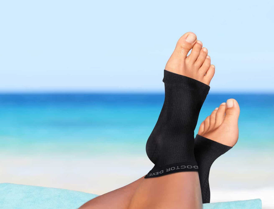 A woman's feet, with foot conditions, resting on a Dr. Arthritis Copper Infused Foot Sleeve (Pair).