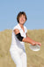 A woman holding a Copper Lined Elbow Support Brace on the sandy beach from Dr. Arthritis.