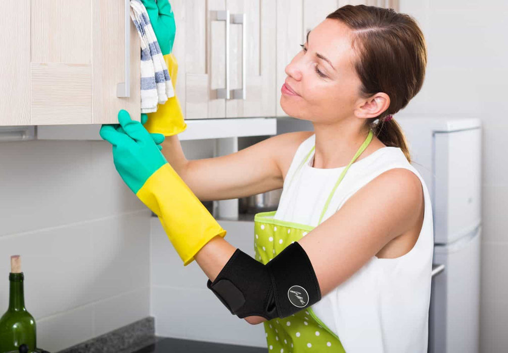 A woman wearing Dr. Arthritis Copper Lined Elbow Support Brace cleaning a kitchen.