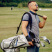 A man holding a golf bag and golf clubs with Dr. Arthritis Copper Lined Golf Wrist Brace [Single] for support.