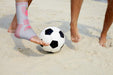 Two individuals engaging in a game of soccer with a Dr. Arthritis Ankle Compression Sleeve on the sandy beach.
