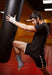 A man kicking a punching bag in a gym while wearing a Dr. Arthritis ankle compression sleeve.