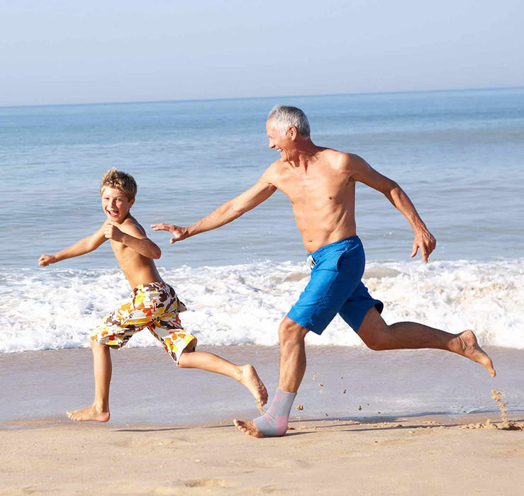 A man and a boy are running by the beach wearing Dr. Arthritis Ankle Compression Sleeves.