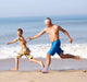 A man and a boy are running by the beach wearing Dr. Arthritis Ankle Compression Sleeves.