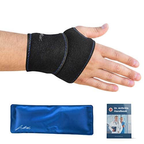 A hand wearing a black wrist support brace for carpal tunnel syndrome, with a blue gel pack and a 'Dr. Arthritis Handbook' visible.