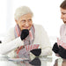 Two elderly women playing cards at a table wearing Dr. Arthritis Copper Compression Gloves (Full-Fingered).
