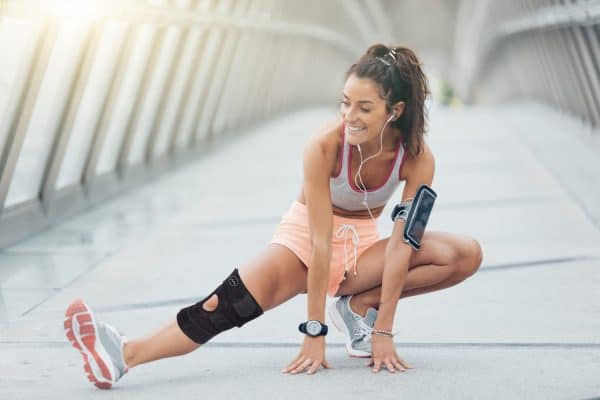 A woman squatting on a bridge while wearing a Dr. Arthritis Copper Lined Knee Support Band for joint support.